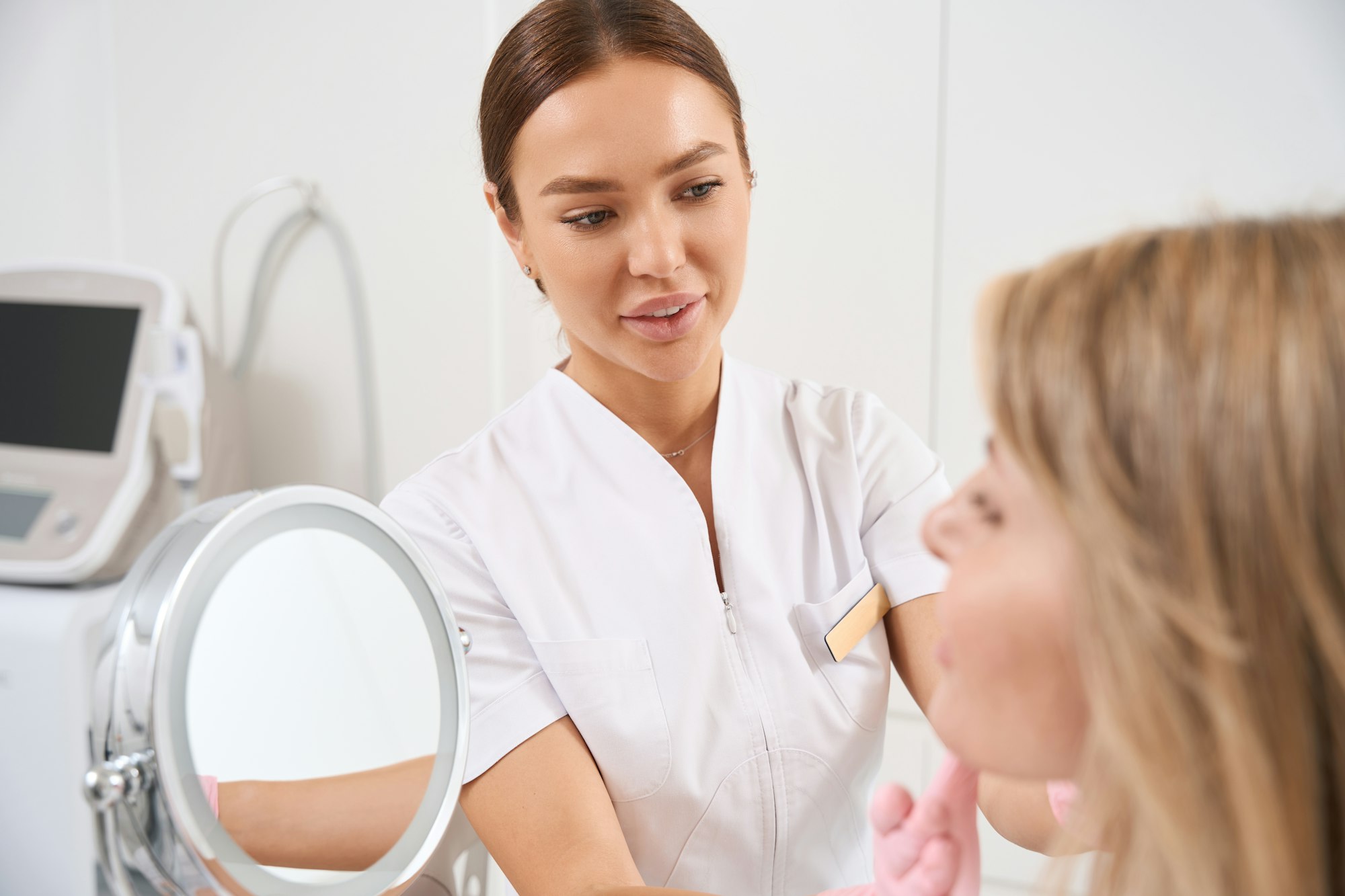 Doctor cosmetologist examines the client of the aesthetic medicine clinic